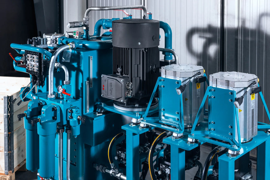 Large blue industrial machine with various components in a workshop setting