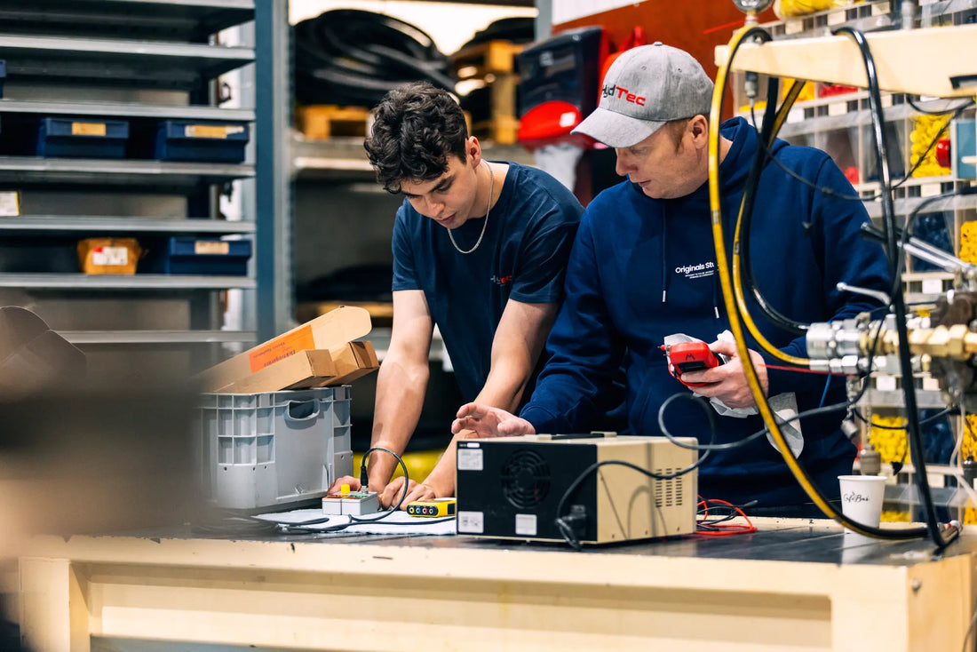 Two technicians working on electronic equipment in a warehouse setting