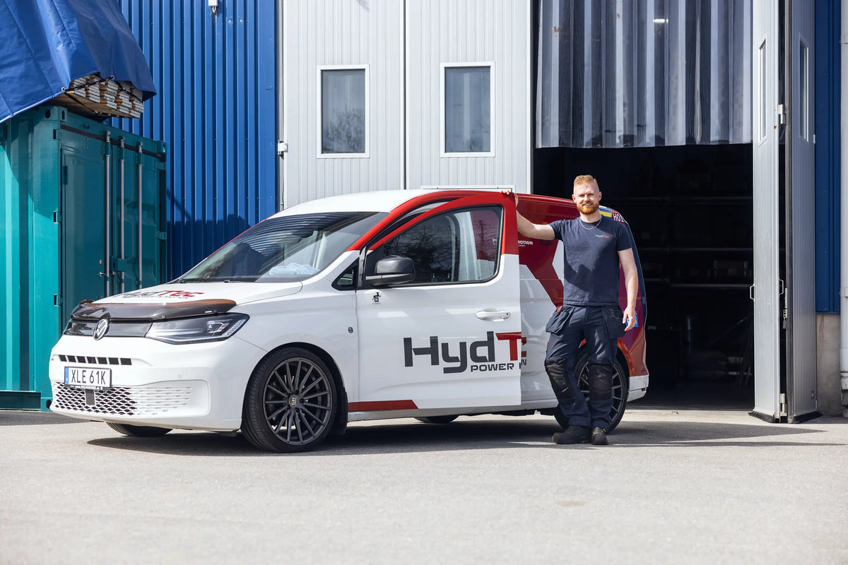 Person standing next to a white van with 'HydTec' branding in front of a building.