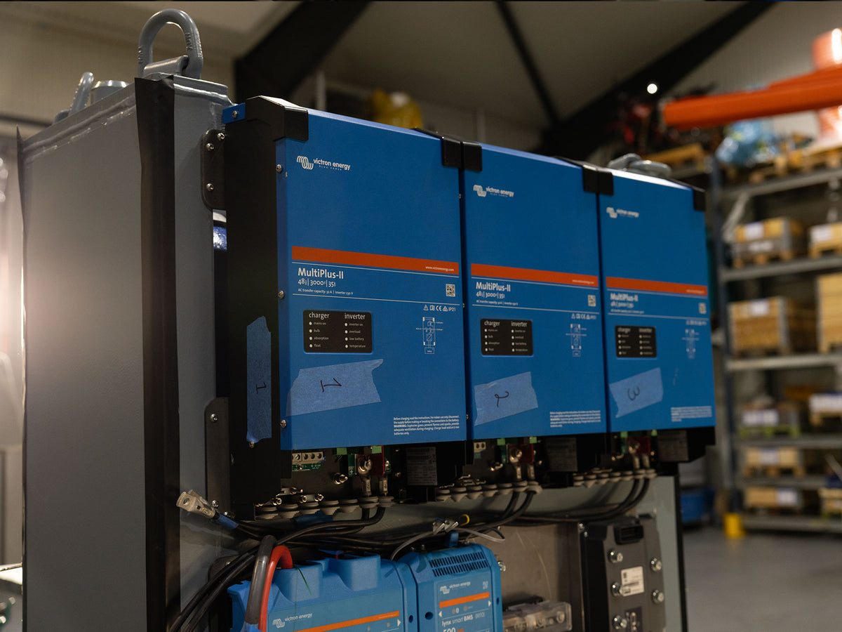 Three blue electrical inverter/charger units assembled together, part of the electrical control system in HydTec's subsea power module build.